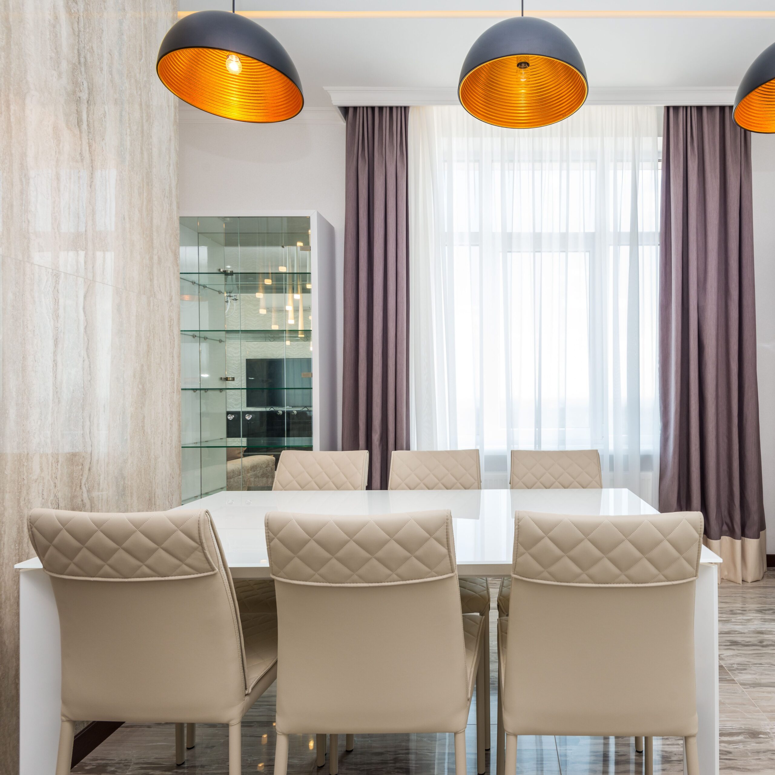 A modern dining room featuring elegant chairs, a white table, and contemporary lighting.